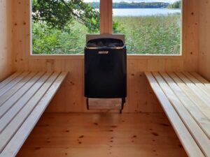 Innenraum einer handgefertigten Holzsauna mit Sitzbänken und Saunaofen.