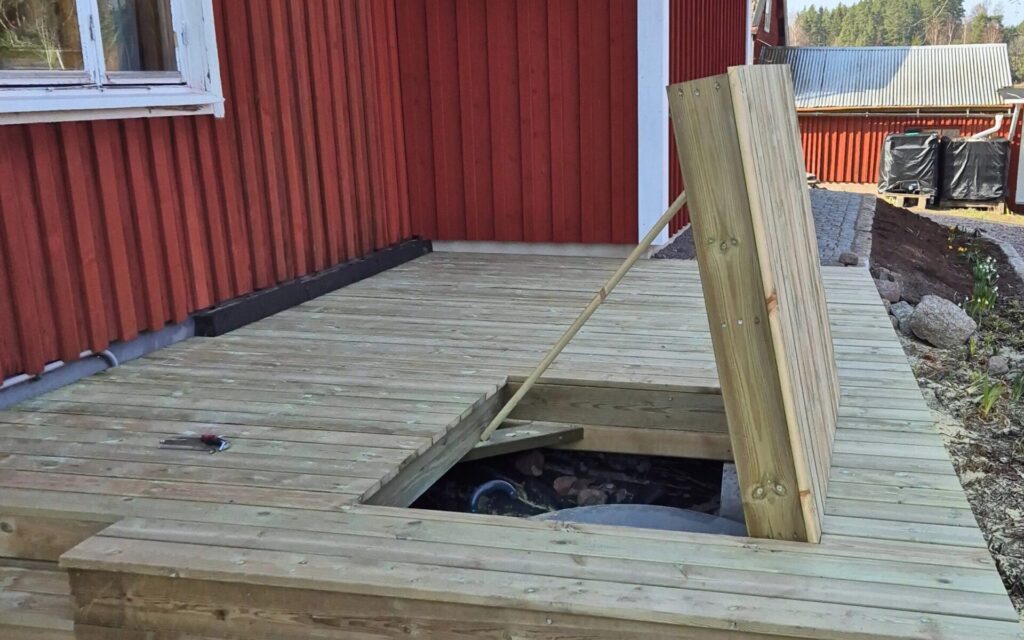 Maßgefertigte Holzluke in Terrasse als Zugang zu bestehendem Wasserbrunnen.