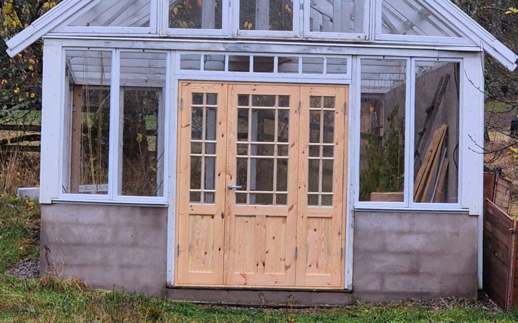 Träkonstruktion med glasdörr i trädgård