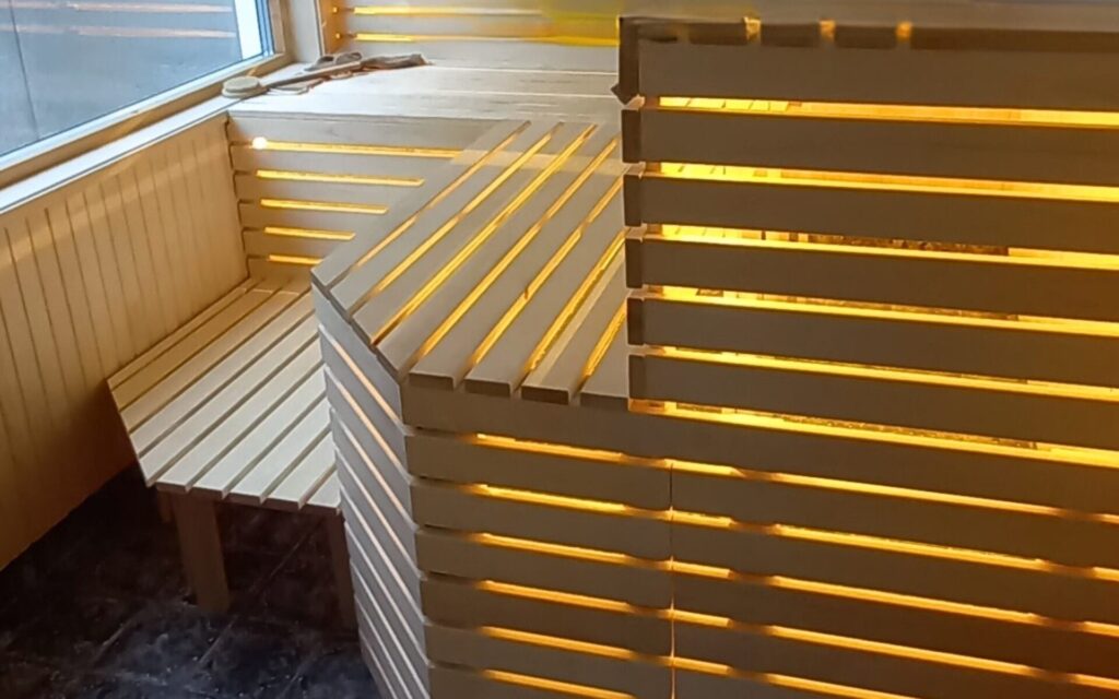 Individuell gefertigter Sauna-Innenausbau aus Holz mit indirekter Beleuchtung.